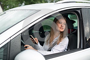 Young business woman driving car and talking on mobile phone