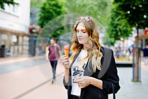 Young business woman eating ice cream. Happy alone woman in in the city on sunny summer day, break for lunch between