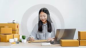 Young business woman entrepreneur writing address on cardboard box