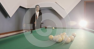 Young business woman in glasses and suit learns to play Russian billiards.