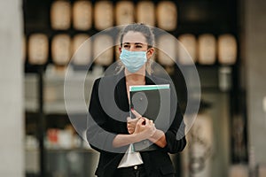 Young business woman going to work down the street wearing medical mask