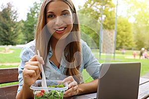 Young business woman have a lunch sitting in city park looking at camera