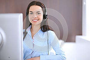 Young business woman in a headset, sitting at the table in the office