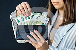 Young business woman holding black wallet with euro banknotes, close up of female hands with cash. The concept of cash payments,