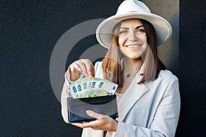 Young business woman holding black wallet with euro banknotes, close up of female hands with cash. The concept of cash payments,