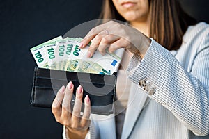 Young business woman holding black wallet with euro banknotes, close up of female hands with cash. The concept of cash payments,