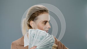 Young business woman holding cash money. Rich girl hold dollar money near face