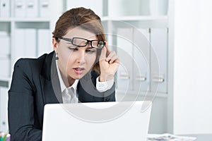 Young business woman looking intently at laptop photo