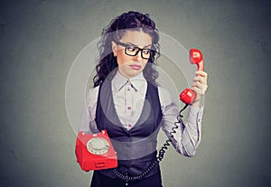 Young business woman looking at a red phone with a suspicious expression