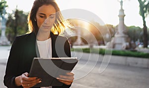 Young business woman looking screen on tablet working in park barcelona sun day, professional finance girl using touch pad on back