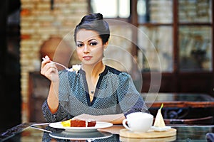Young business woman on lunch break in cafe or restaurant holding a fork and smiling