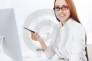 Young business woman and man sitting and working with computer and calculator in office. Bookkeeper checking balance or