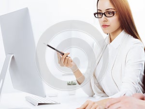 Young business woman and man sitting and working with computer and calculator in sunny office. Bookkeeper checking