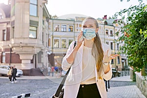Young business woman in medical protective mask talking on smartphone