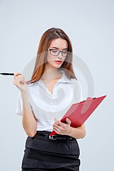 The young business woman with pen and tablet for notes on gray background