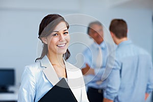 Young business woman. Portrait of beautiful business woman smiling with associates discussing in background.