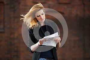Young business woman reading a tax letter on city street