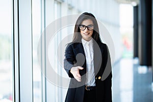 Young business woman ready to handshake standing in modern office