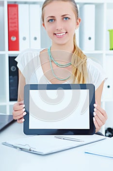 Young business woman showing blank screen of tablet pc in office.