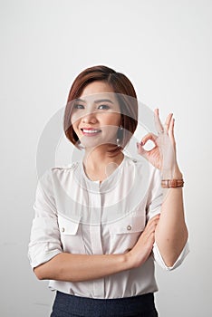 Young business woman showing OK sign on white background