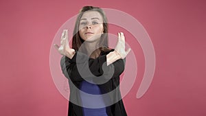 Young business woman showing stop sign against pink background. Denying, rejecting, disagree.