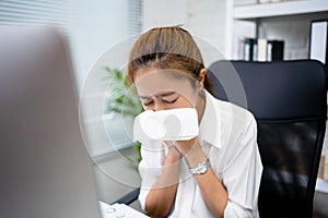 Young business woman is sick. She sneezes and coughs in the office photo