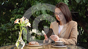 Young business woman sits in a cafe and writes text messages on a tablet.