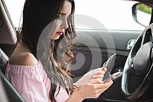 Young business woman sitting in car using mobile phone.