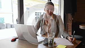 Young business woman sitting in the coffee shop during the lunch break drinking coffee and work on the laptop computer. Freelancer