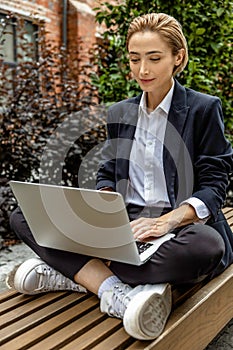 Young business woman sitting in a lotus pose and working on laptop