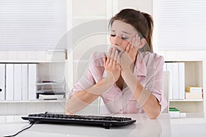 Young business woman sitting tired and yawning in the office.