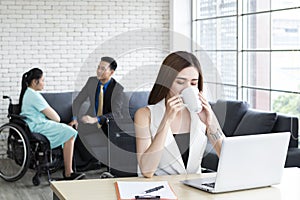 Young business woman sitting on workplace drinking coffee. Attractive young businesswoman working on laptop in her workstation in