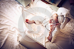 Young business woman taking business calls from bed.