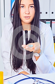 Young business woman taking medicine in a stressful situation at workplace. Woman consults on the phone with her doctor