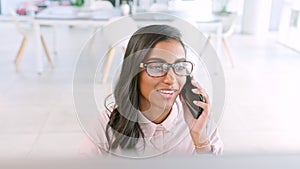 Young business woman taking a phone call while working in a modern office. Professional female consultant typing on