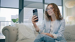 Young business woman talking on phone using front mobile camera for video chat