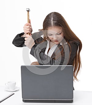 Young business woman trying to smash the laptop with a hammer