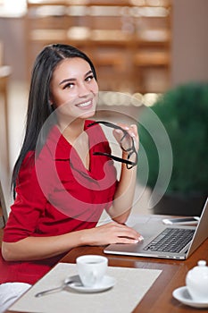 Young business woman uses laptop in cafe