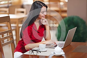 Young business woman uses laptop in cafe