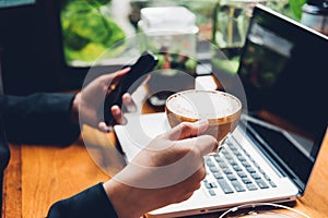 Young business woman is using his smart phone and The laptop computer