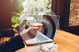 Young business woman is using his smart phone and The laptop computer