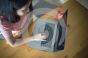 Young business woman using laptop computer working on wooden table with copy space. Asian girl typing on notebook in coffee shop,