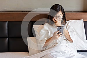 Young business woman using moble phone on bed while working from home during covid -19 crisis
