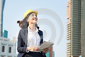 Young business woman using a tablet in the street with office bu