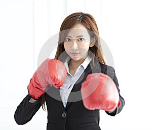 Business woman wearing boxing gloves ready to fight