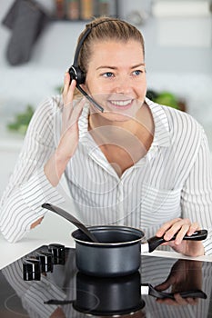 young business woman working while cooking meal in kitchen