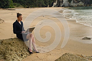 A young business woman working on her laptop at the beach