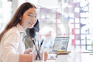Young business woman working with laptop and analyzing business report document in co-working or coffee shop. Business people work