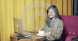 Young business woman working on laptop at coffee shop. Man waiter serving a cup of hot cappuccino to female customer in cafe