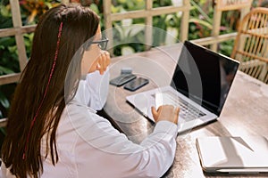 Young business woman working on laptop in outdoor cafe